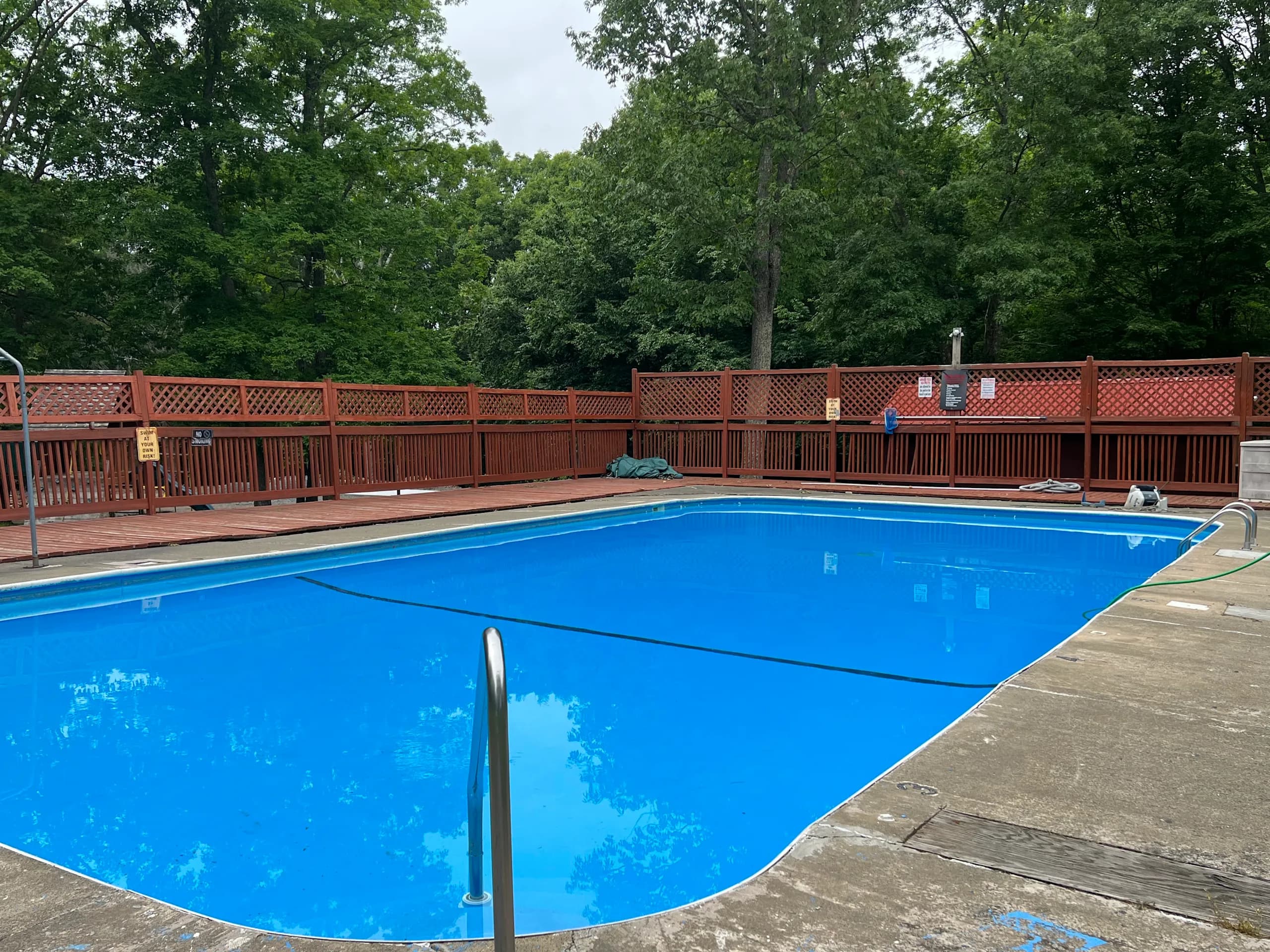Outdoor swimming pool surrounded by wooden decking and tall trees at Big Bear Private Community in the Poconos.